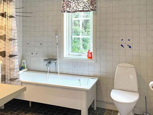 een badkamer met een bad, een toilet en een raam bij Holiday home HJO III in Hjo