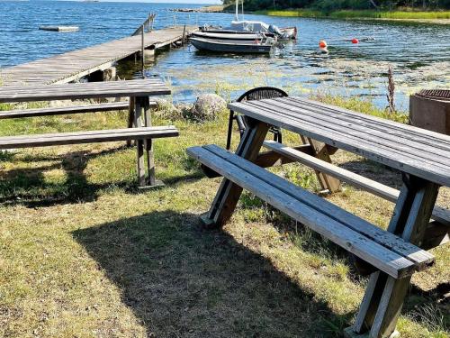 two wooden benches sitting next to a dock with a boat at 7 person holiday home in Hagby-By Traum in Hagby