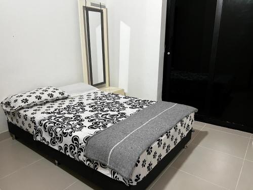 a bed with a black and white blanket and a mirror at EL MILAGRO FINCA VACACIONAL in San Rafael