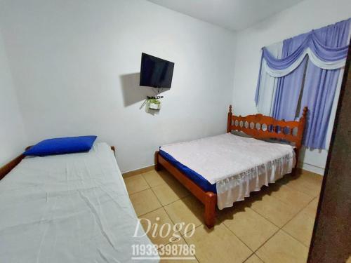 a bedroom with two beds and a tv on the wall at Casa Praia Grande WIFI 2dorm 2ban 2carr churrasq 400mts da praia Tupi in Praia Grande