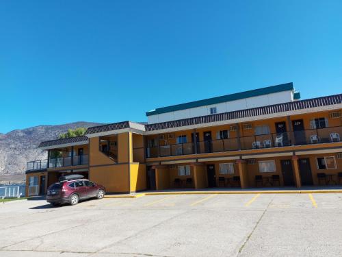 a building with a car parked in a parking lot at Richter Pass Beach Resort in Osoyoos