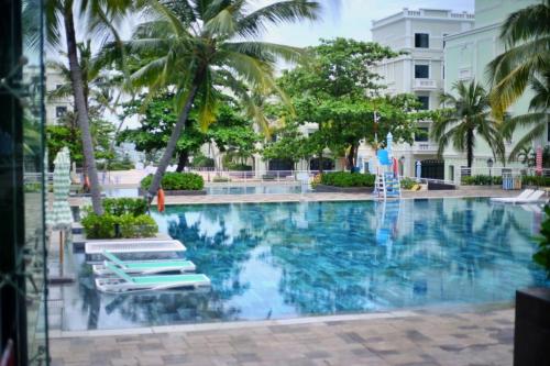 una piscina en un hotel con sillas y palmeras en Elene Phu Quoc en Phu Quoc
