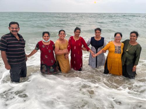 a group of people standing in the water at the beach at Marari Beach Villas in Mararikulam