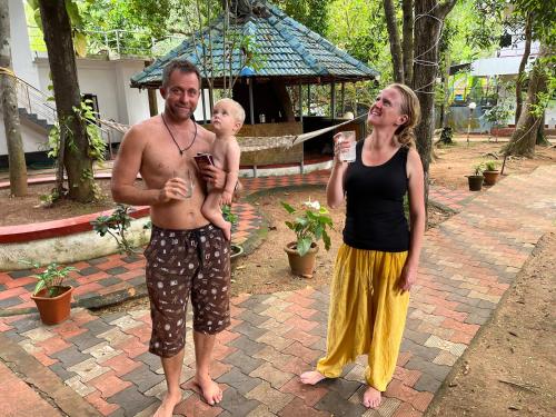 a man holding a baby and a woman holding a drink at Marari Beach Villas in Mararikulam