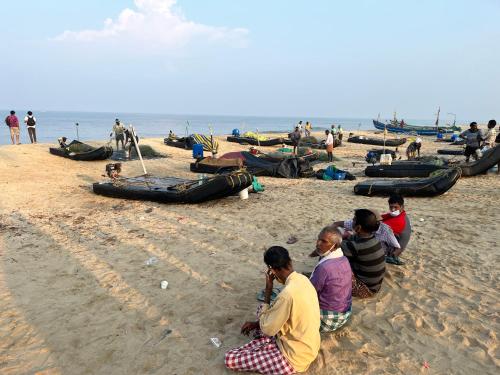 a group of people sitting on a beach at Marari Beach Villas in Mararikulam