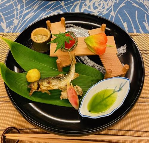 a black plate of food on a table at ひがし茶屋街らしく金沢 Hotel Rashiku kanazawa in Kanazawa