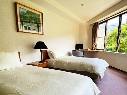 Cette chambre comprend 2 lits et une fenêtre. dans l'établissement Hotel & Onsen 2307 Shigakogen, à Yamanouchi