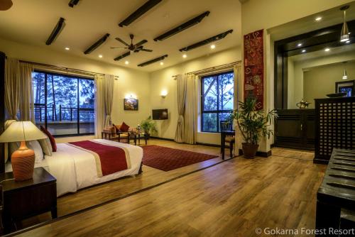 a bedroom with a bed and a desk and windows at Gokarna Forest Resort Kathmandu in Kathmandu