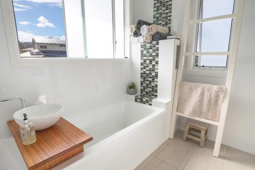 a white bathroom with a tub and a sink at Diggers Beach Villa Coffs Harbour in Coffs Harbour