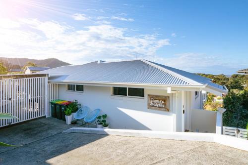 a white house with a fence and two chairs at Diggers Beach Villa Coffs Harbour in Coffs Harbour