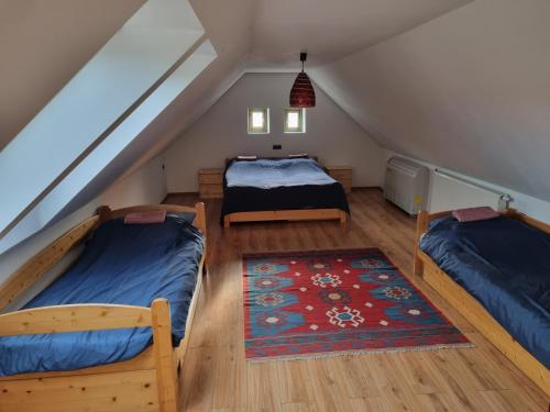 a attic bedroom with two beds and a rug at Tulipános Palkonya in Palkonya