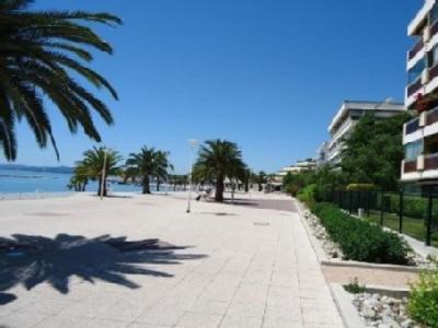 a sidewalk with palm trees and a building and the ocean at Maeva in Saint-Laurent-du-Var