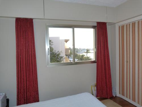 a bedroom with red curtains and a bed and a window at Maeva in Saint-Laurent-du-Var