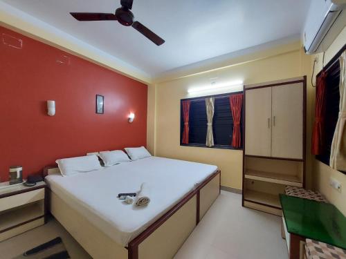 a bedroom with a large white bed and a red wall at Mira International in Digha