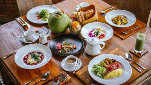 a wooden table with plates of food on it at The Alena a Pramana Experience in Ubud