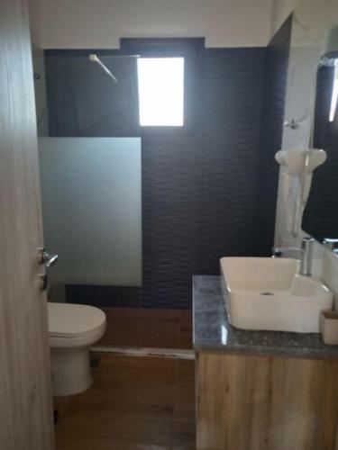 a bathroom with a white toilet and a sink at Kamares View (Απέραντο Γαλάζιο) in Ayeranós