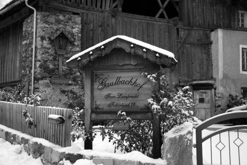 un panneau dans la neige devant une maison dans l'établissement Gaulbachhof, à Naturno