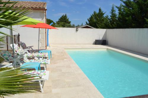 een zwembad met stoelen en een parasol ernaast bij Joli appartement au calme entre Nîmes et Avignon in Meynes