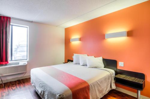 a hotel room with a bed with an orange wall at Motel 6-Lansing, IL - Chicago South in Lansing