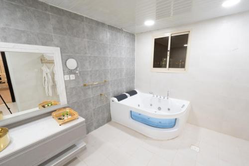 un bagno bianco con vasca e lavandino di المرجانة للوحدات السكنية a Rafha