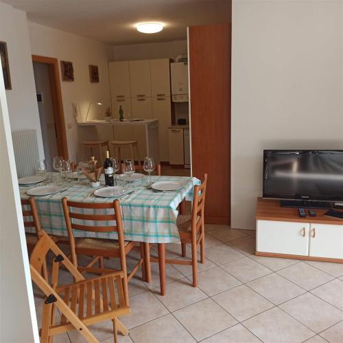 a dining room with a table and chairs and a television at Juli Richi apartment in Croviana
