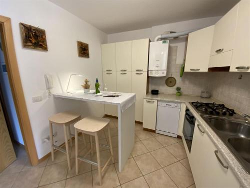 a kitchen with white cabinets and a counter with stools at Juli Richi apartment in Croviana
