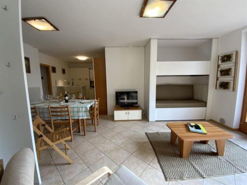 ein Wohnzimmer mit einem Sofa und einem Tisch sowie eine Küche in der Unterkunft Juli Richi apartment in Croviana