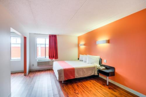 a room with a bed with an orange wall at Motel 6-Lansing, IL - Chicago South in Lansing