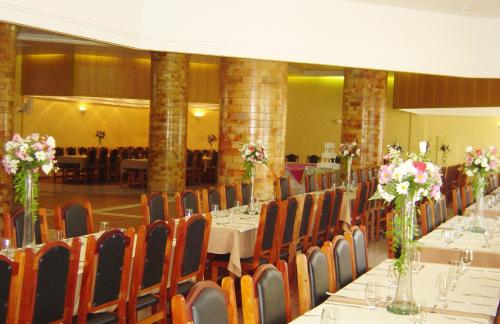 a dining room with tables and chairs with flowers in vases at Hara Palace Hotel in Curitiba