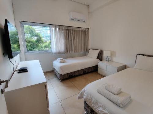 een hotelkamer met 2 bedden en een raam bij Begin19 Apartments & Hostel in Tel Aviv