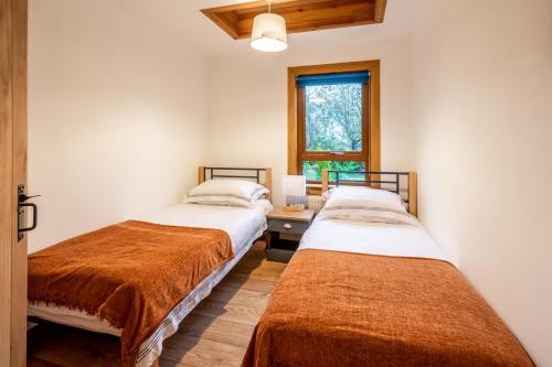 two beds in a room with a desk and a window at Coorie View in Kilmore