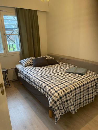 a bedroom with a bed with a plaid blanket and a window at Villa Haantie in Längelmäki