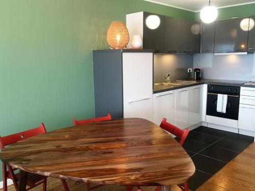 une cuisine avec une table en bois et des chaises rouges dans l'établissement Superbe T4 avec emplacement n°1 face à la mer!, à Le Touquet-Paris-Plage