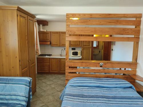 una cocina con armarios de madera y una cama en una habitación en Residenza L'Teit en Sestriere