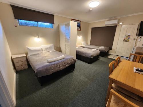 a hotel room with two beds and a table at Hume Inn Motel Albury CBD in Albury