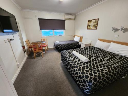 a hotel room with a bed and a chair and a table at Hume Inn Motel Albury CBD in Albury