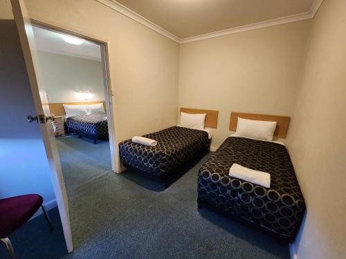 a small room with two beds and a mirror at Hume Inn Motel Albury CBD in Albury