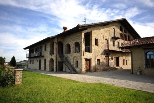 un grande edificio in pietra con un prato davanti di Casapecchenino a Dogliani