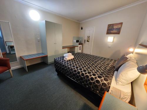 a small hotel room with a bed and a chair at Hume Inn Motel Albury CBD in Albury