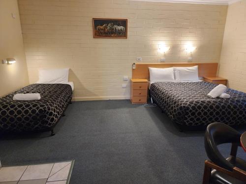 a hotel room with two beds and a desk at Hume Inn Motel Albury CBD in Albury