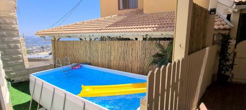 a swimming pool with a slide in a backyard at Vida Bhermon 2, one small wooden cabin in Majdal Shams