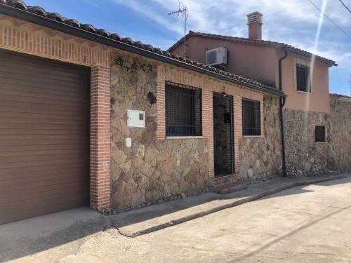 a brick building with a garage door on a street at El huerto de Lino in Candeleda