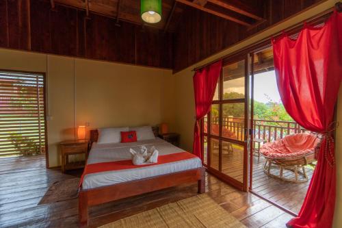 a bedroom with a bed and a balcony with red curtains at Ratanakiri Paradise Hotel & Restaurant in Banlung