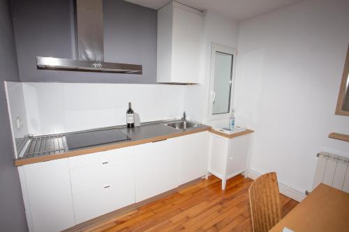 eine Küche mit weißen Schränken, einer Spüle und einem Tisch in der Unterkunft LA MARINA amplio apartamento en pleno centro de Hondarribia in Hondarribia