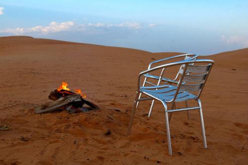 a chair sitting next to a fire in the desert at Rashid Desert Private Camp in Bidiyah