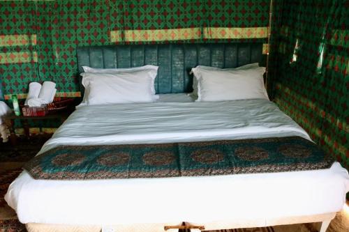 Cama en habitación con pared verde en Rashid Desert Private Camp en Badīyah