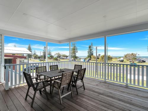 a porch with a table and chairs on a balcony at Beachside at Brooms in Brooms Head