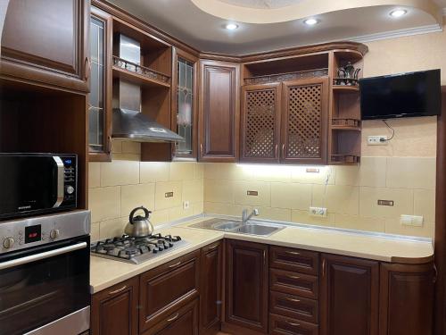 a kitchen with wooden cabinets and a sink and a stove at Boryspil Airport Luxury apartment in Boryspilʼ