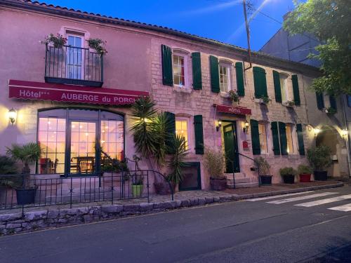 a pink building with green shutters on a street at AUBERGE DU PORCHE in Blaye