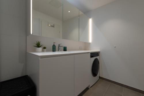 a white bathroom with a sink and a washing machine at Grüne Oase an der Therme in Vienna